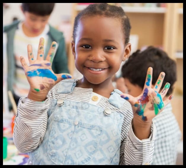 A young child with painted hands at a creative-arts session